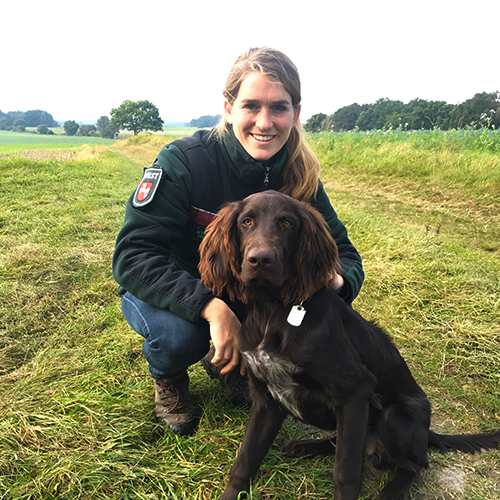Junge Försterin mit Hund auf Wiese