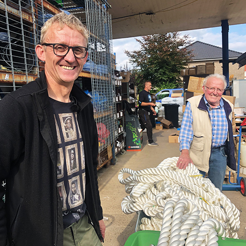 Zwei Männer, einer jung, der andere alt, stehen vor einem Supermarkt mit Seilen