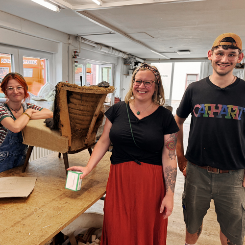 Drei Personen in Polsterei mit Sessel auf einem Tisch