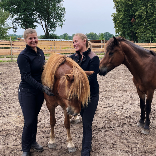 Zwei junge Frauen stehen mit zwei Ponys auf einem Ponyhof